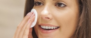 Beautiful brunette woman removing makeup from her face